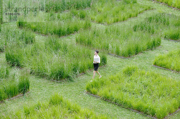 Junge Büroangestellte beim Spaziergang durch das Graslabyrinth