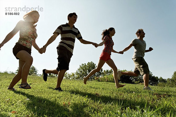 Gruppe junger Erwachsener beim Händchenhalten und Laufen