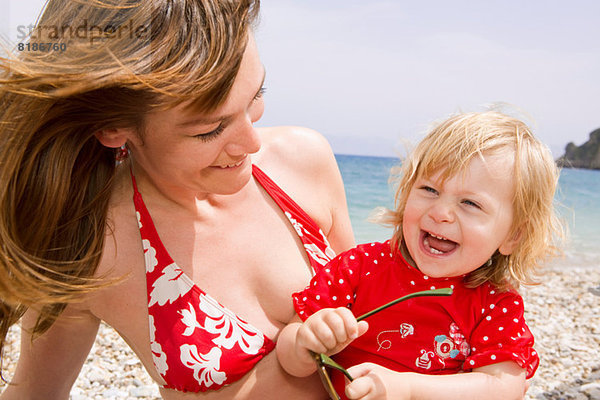 Mutter und Tochter lächeln am Strand