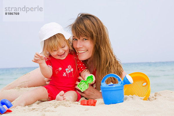 Mutter und Tochter spielen am Strand