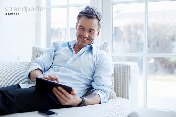 Mann entspannt auf dem Sofa mit digitalem Tablett