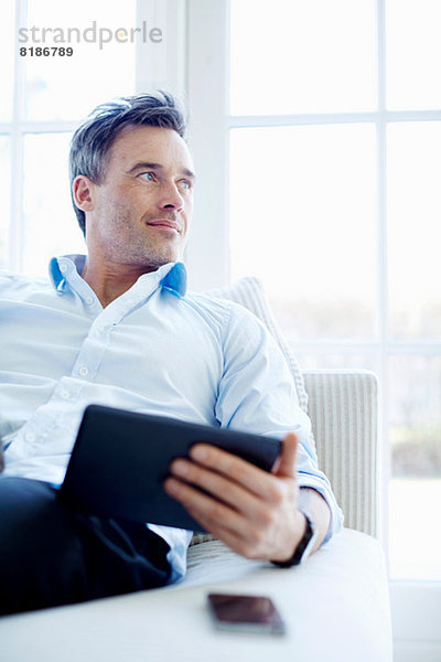 Mann auf Sofa sitzend mit digitalem Tablett
