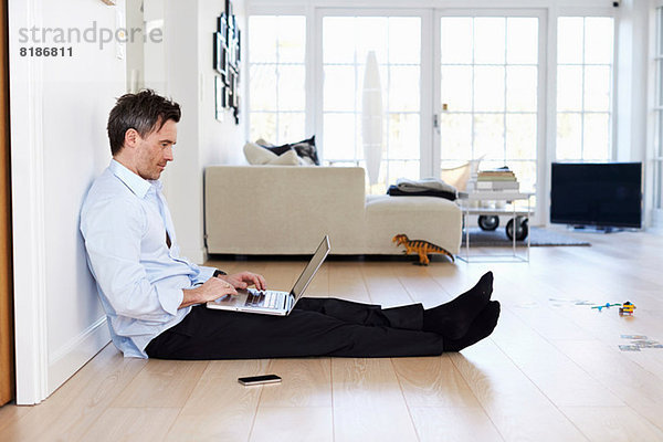 Mann auf dem Boden sitzend mit Laptop