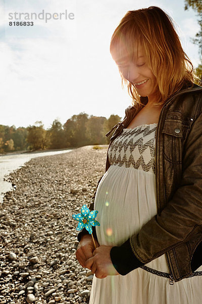 Schwangere Frau am Fluss stehend mit Windmühle