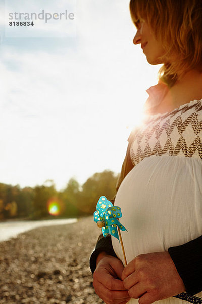 Schwangere Frau am Fluss stehend mit Windmühle