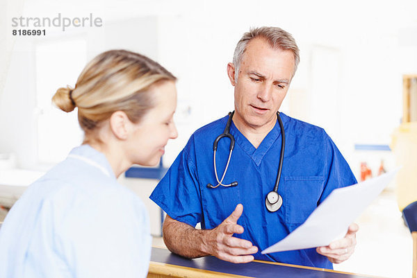 Arzt und Krankenschwester beim Betrachten von Notizen