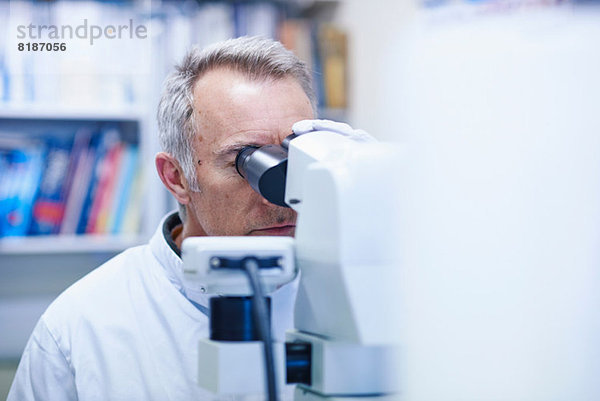 Mann schaut durchs Mikroskop
