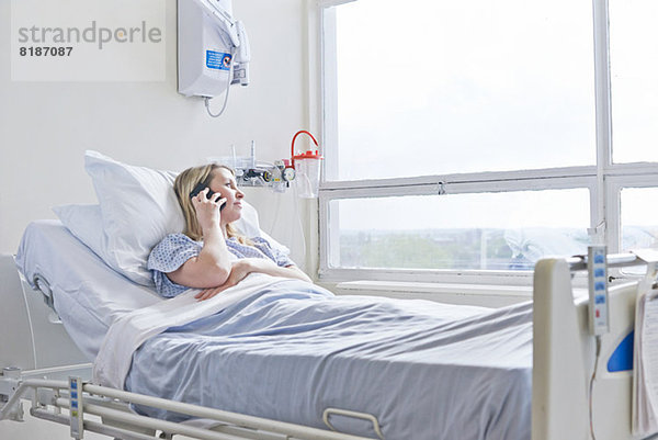 Patient liegt auf dem Krankenhausbett bei Telefonanruf