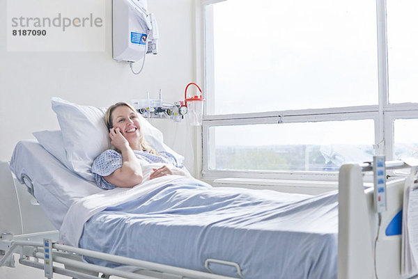 Patient liegt auf dem Krankenhausbett bei Telefonanruf