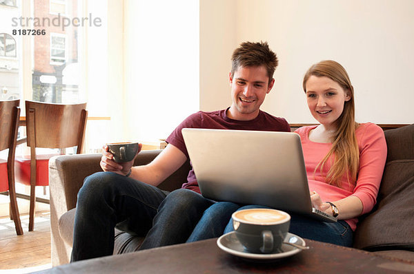 Junges Paar beim Betrachten des Personalcomputers im Café