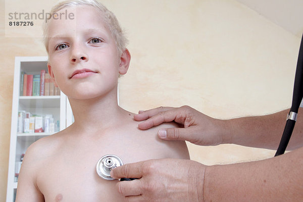 Junge wird vom Arzt mit Stethoskop untersucht