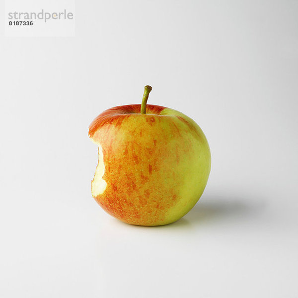 Ein Apfel auf weißem Grund mit Bissmarkierung