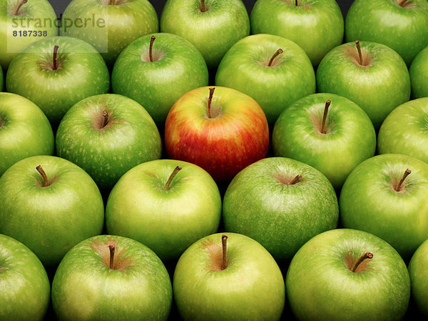 Gruppe grüner Äpfel mit einem roten Apfel