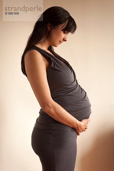 Schwangere Frau meditiert  während sie den Bauch hält.