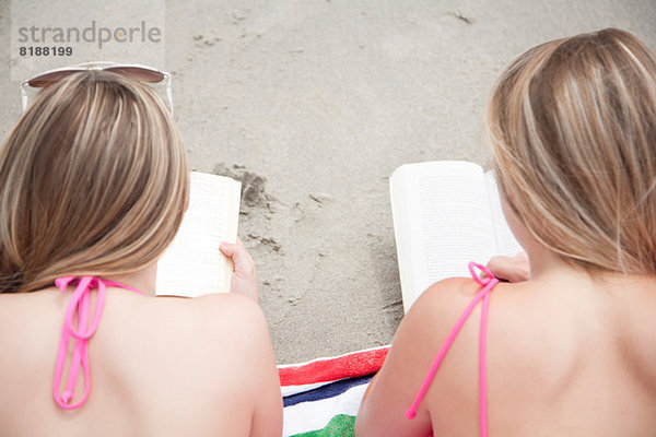 Junge Frauen beim Lesen von Büchern am Strand