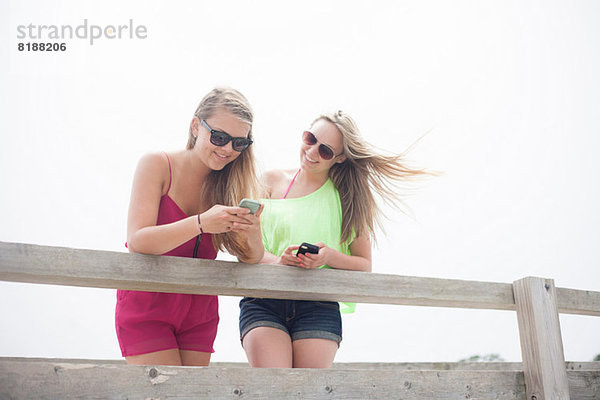 Junge Frauen benutzen Mobiltelefone am Pier