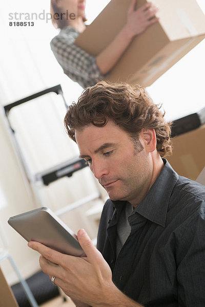 Mann schaut auf das digitale Tablett  während er nach Hause geht.