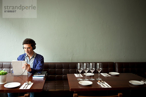 Junger Mann mit Kopfhörer im Restaurant