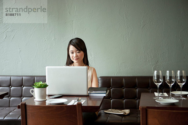 Junge Frau mit Laptop im Restaurant