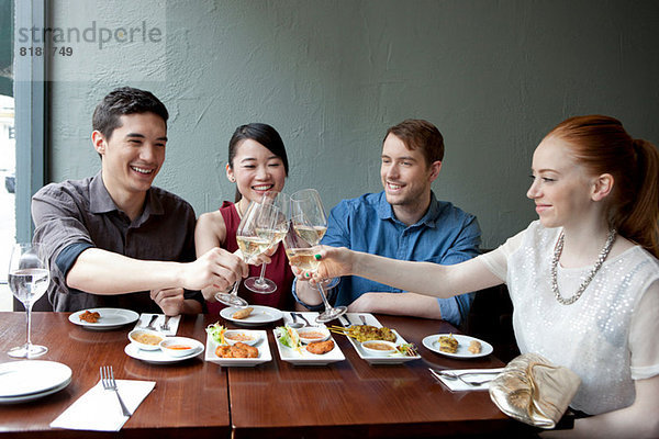 Vier Freunde toasten Weißwein im Restaurant