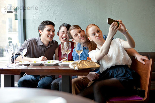 Vier Freunde fotografieren sich im Restaurant