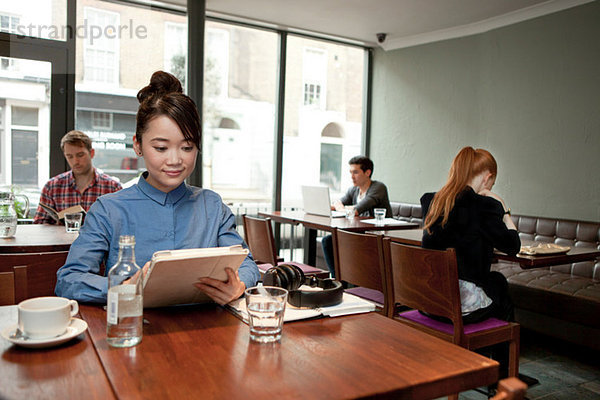 Junge Frau mit digitalem Tablett im Cafe