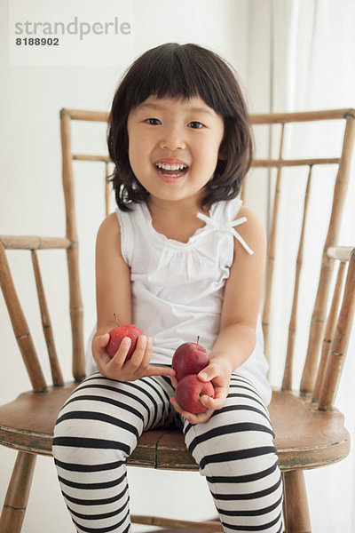 Mädchen auf Holzstuhl sitzend mit Äpfeln  Portrait