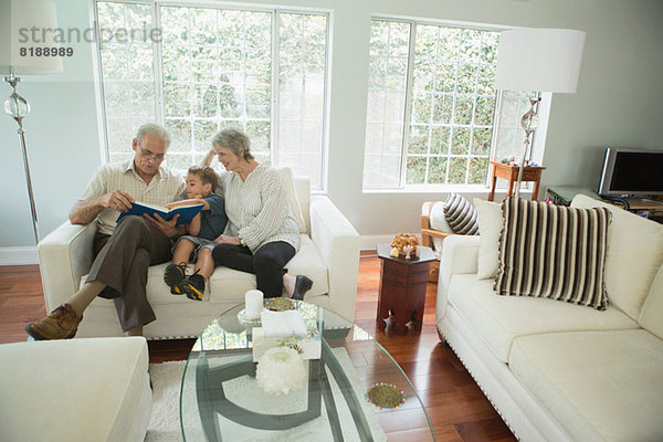 Großeltern zeigen Jungen-Fotoalbum auf Sofa