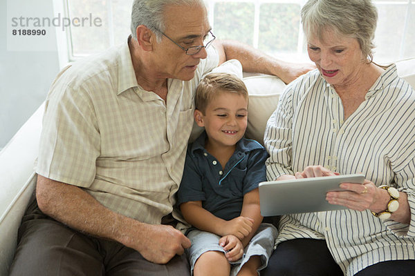 Großeltern zeigen Jungen digitales Tablett auf Sofa