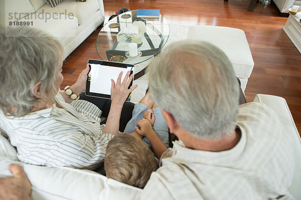 Großeltern zeigen Jungen digitales Tablett auf Sofa