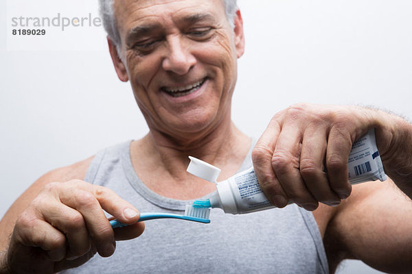 Senior Mann drückt Zahnpasta auf die Bürste
