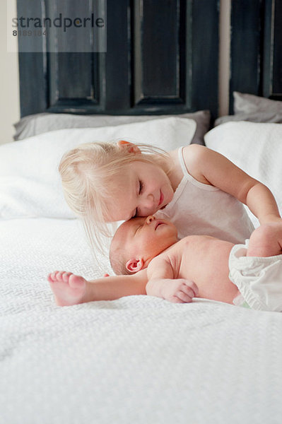 Mädchen sitzend mit Baby-Bruder im Bett