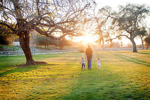 Vater wandert mit Sohn und Tochter im sonnigen Feld