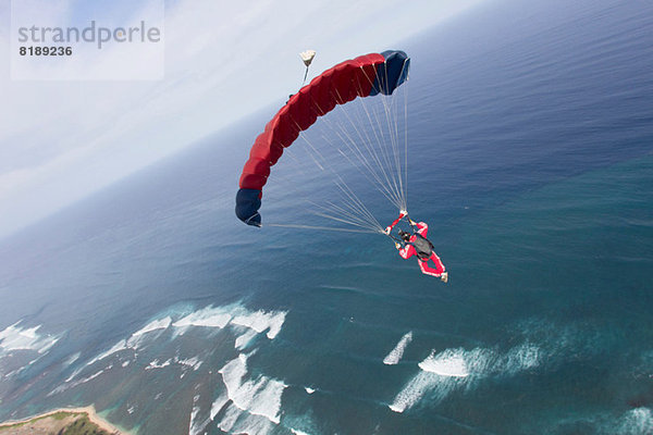 Fallschirmspringer mit rotem Fallschirm über Honolulu  Hawaii