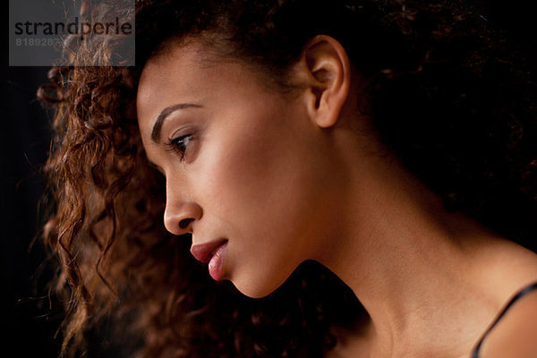 Junge Frau im Profil vor schwarzem Hintergrund