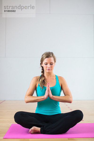 Junge Frau auf Yogamatte in Lotusstellung