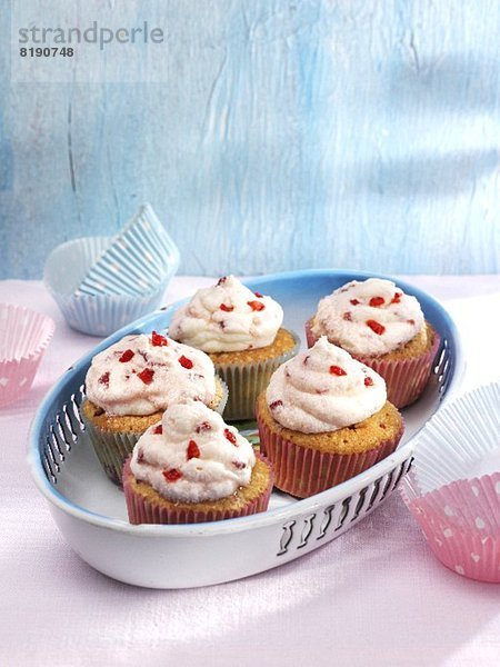 Cupcakes mit Fruchtcreme in rosa und blauen Papierförmchen