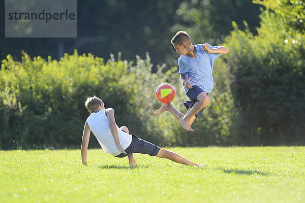 Zwei Teenager spielen Fußball auf der Wiese  Oberpfalz  Bayern  Deutschland  Europa