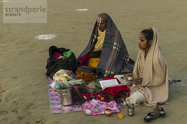 Priester mit seiner Tochter beim Meditieren  während der Kumbha Mela