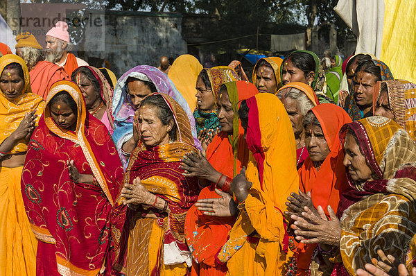 Gruppe von bunt-gekleideten betenden Frauen während der Kumbha Mela