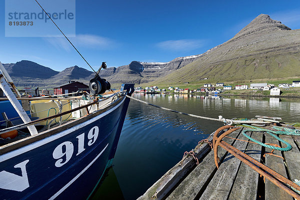 Fischerboot und rostige Anker im Hafen von Hvannasund  hinten die Ortschaft Norðdepi