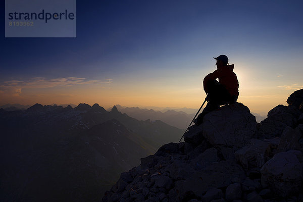 Bergsteiger sitzt auf einem Felsen auf dem Großen Krottenkopf  Abenddämmerung