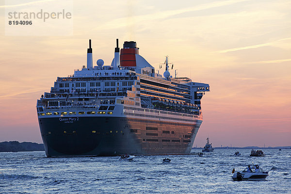 Kreuzfahrtschiff MS Queen Mary 2 läuft bei Sonnenuntergang auf der Elbe aus dem Hamburger Hafen aus