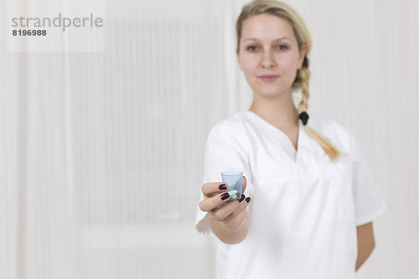 Deutschland  Portrait einer jungen Frau mit Medizinbecher