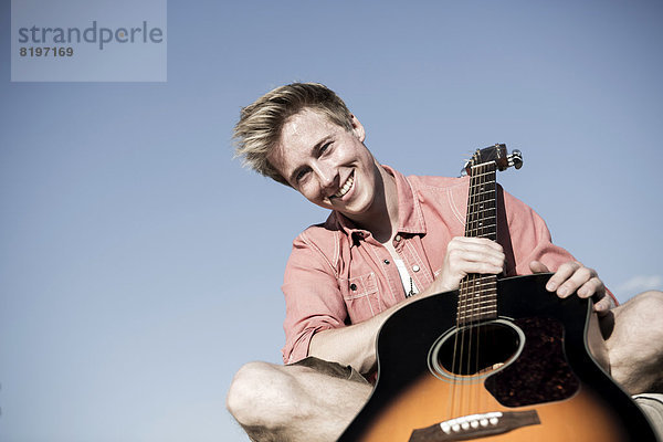 Germany  Young man holding guitar  smiling