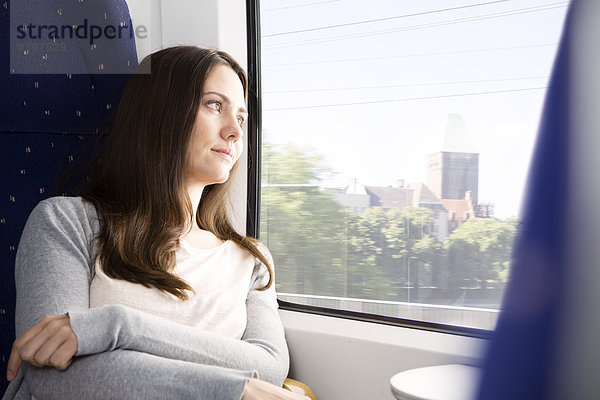 Mittlere erwachsene Frau mit Blick durchs Fenster im Zug