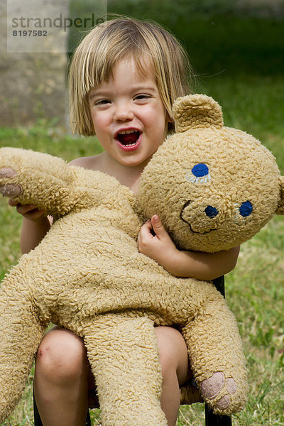 Deutschland  Baden Württemberg  Porträt eines Mädchens  das mit Teddybär spielt  lächelnd