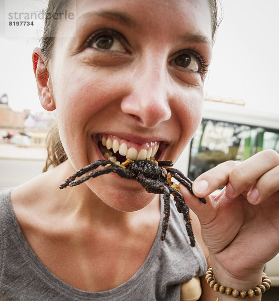 Kambodscha  Junge Frau isst gebratene Vogelspinnen