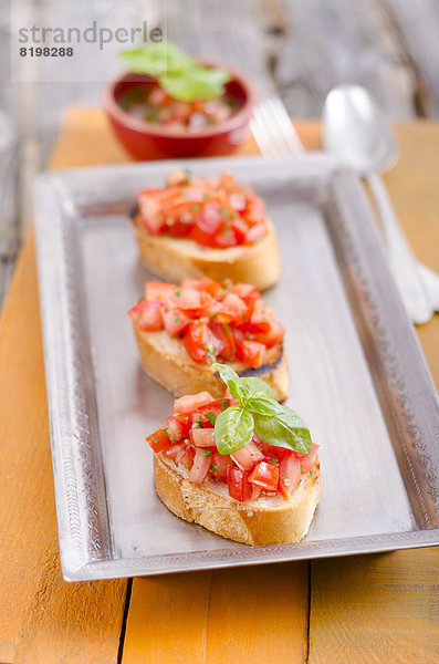 Bruschetta mit Tomaten und Basilikum auf dem Tablett  Nahaufnahme