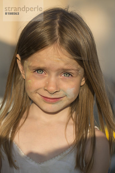 Porträt eines lächelnden Mädchens mit farbiger Kreide im Gesicht